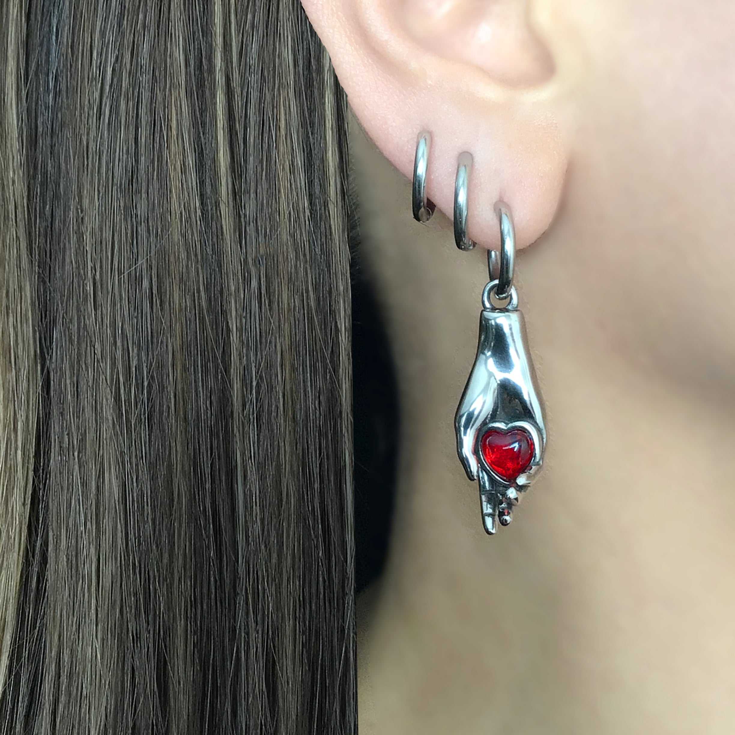 Hand holding Heart hoop earrings in Silver